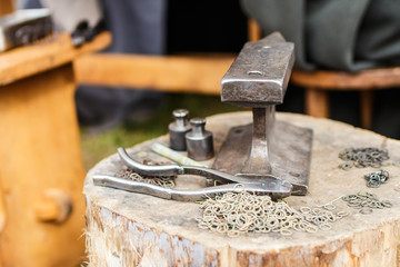 An anvil with tools and lot of rings for chain mail. Close up view, shallow depth of field