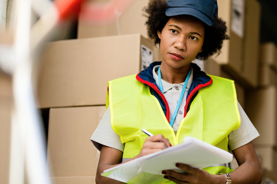 African American Delivery Woman Going Through Shipment List.