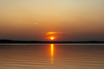 sunset on the background of the sea. the sun sets over the horizon, leaving glare on the water.