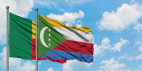 Benin and Comoros flag waving in the wind against white cloudy blue sky together. Diplomacy concept, international relations.