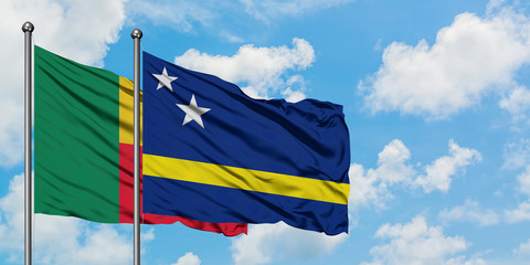 Benin and Curacao flag waving in the wind against white cloudy blue sky together. Diplomacy concept, international relations.