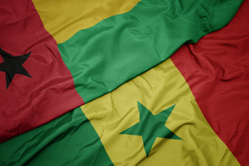 waving colorful flag of senegal and national flag of guinea bissau.
