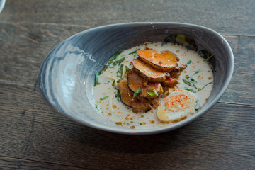 Tom Kha Gai - Thai coconut milk soup with pieces of chicken in a beautiful plate of unusual shape