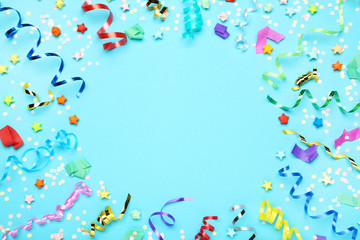 Colorful ribbons with paper stars and confetti on blue background