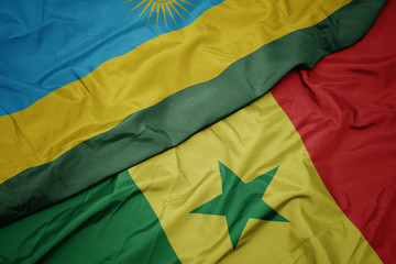 waving colorful flag of senegal and national flag of rwanda.