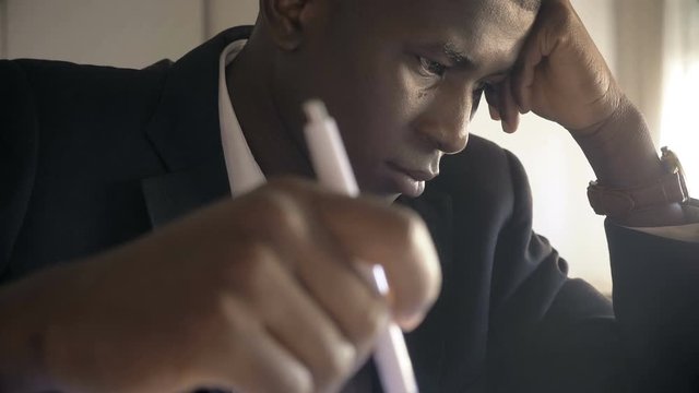 Concentrated succesful black business man working in his office,tickling pen 