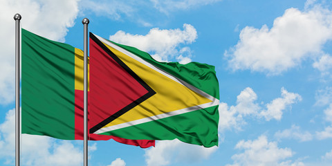 Benin and Guyana flag waving in the wind against white cloudy blue sky together. Diplomacy concept, international relations.