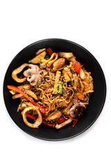 grilled octopus baby, mussels, squid rings and vegetables mix, noodles in sauce, red pepper, sesame seeds in a black plate isolated on white background, top view