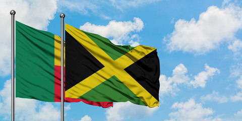 Benin and Jamaica flag waving in the wind against white cloudy blue sky together. Diplomacy concept, international relations.