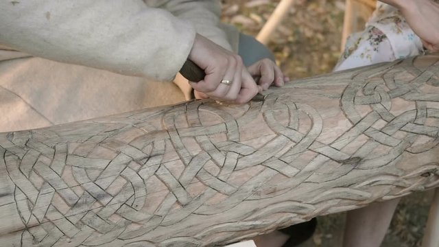 A woodcarver carves ornate complicated patterns on a wooden log. Close up amazing woodcarving