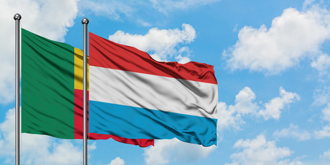 Benin and Luxembourg flag waving in the wind against white cloudy blue sky together. Diplomacy...