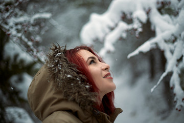 Beautiful woman with dyed red hair outdoors surrounded by snow.  Hipster woman enjoying the snow