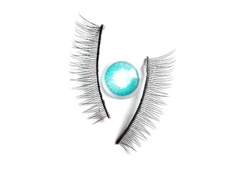 Colored contact lens and artificial eyelashes on a white background, flat lay. Abstract minimal ophthalmology concept.