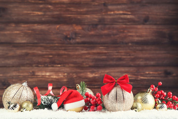 Christmas balls with fir tree branches and red berries on brown wooden background