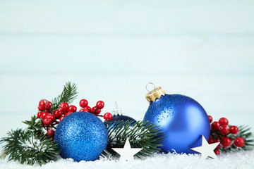 Christmas balls with fir tree branches and red berries on wooden background