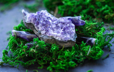 Purple amethyst gemstone and geode on bright green moss