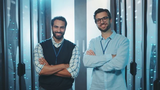 Professional team of caucasian server specialists crossing arms smiling enjoying work in futuristic server room of data center. Cooperation concept.