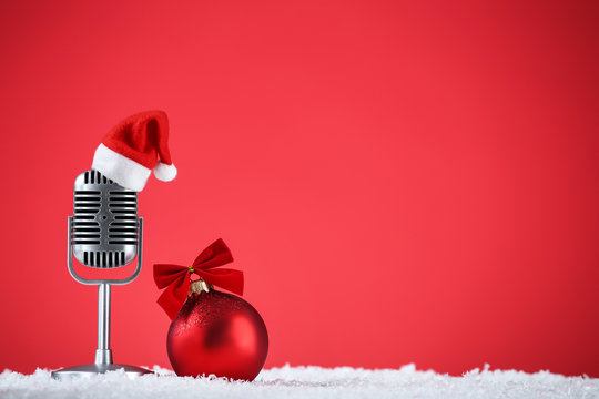 Retro microphone with santa hat and bauble on red background