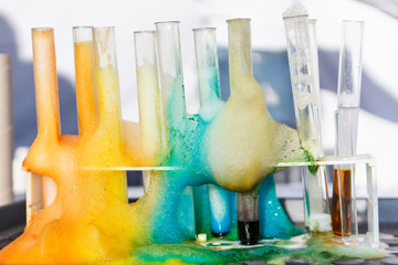 Glass test tubes with liquid in it and colorful foam in science research lab. Failed experiment...