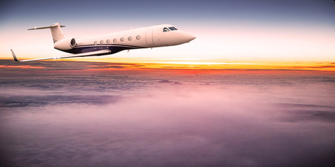 Private jet plane flying above dramatic clouds during sunset.