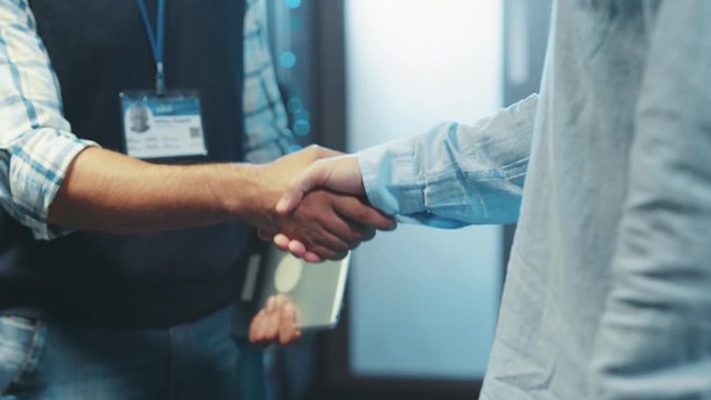 Close-up business people server engineers shaking hands of agreement welcoming partnership working together in rac server room of data center. Collaboration concept.