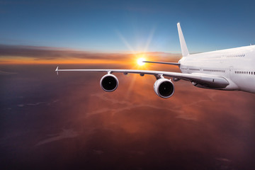Fototapeta na wymiar Big commercial airplane flying above dramatic clouds during sunset.