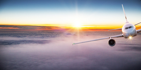 Fototapeta premium Commercial airplane flying above dramatic clouds during sunset.