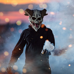 guy in devil mask standing with smoke bombs, portrait
