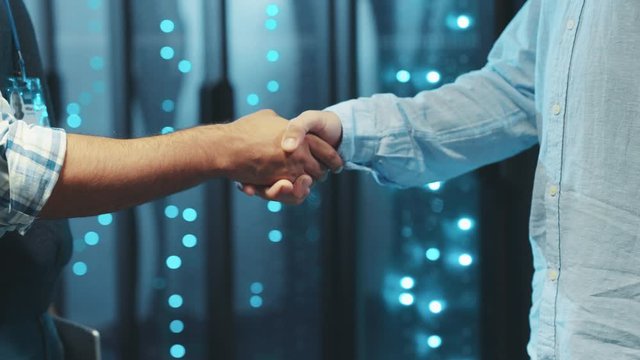 Two engineers business people shaking hands on successful deal corporate partnership agree for cooperation in server room of data center.