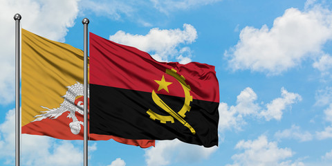 Bhutan and Angola flag waving in the wind against white cloudy blue sky together. Diplomacy...