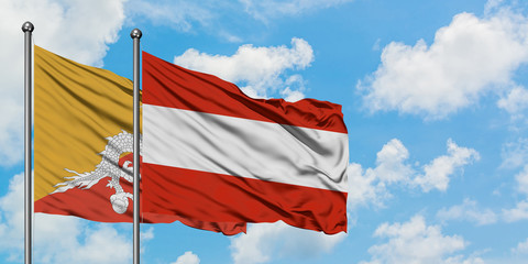 Bhutan and Austria flag waving in the wind against white cloudy blue sky together. Diplomacy concept, international relations.