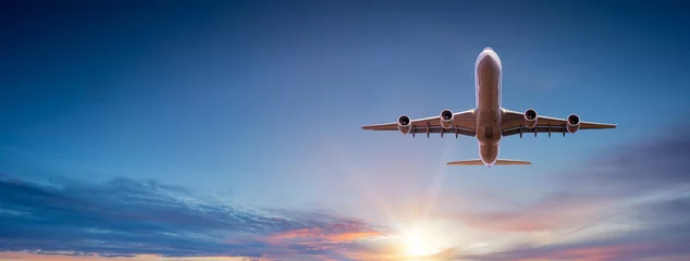 Foto auf Acrylglas Flugzeug Verkehrsflugzeug, das während des Sonnenuntergangs über dramatische Wolken fliegt.