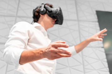 Young excited Man wearing virtual reality goggles in modern bright co-working office. the VR experience.