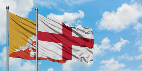 Bhutan and England flag waving in the wind against white cloudy blue sky together. Diplomacy concept, international relations.