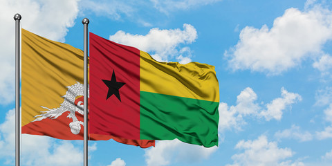Bhutan and Guinea Bissau flag waving in the wind against white cloudy blue sky together. Diplomacy concept, international relations.
