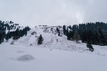An alpine snow slope with a fallen avalanche. Big mass of snow falling down a mountain.
