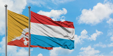Bhutan and Luxembourg flag waving in the wind against white cloudy blue sky together. Diplomacy concept, international relations.