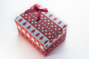 Red Christmas box with gifts on a white background with a top view of Christmas trees. There is a bow in the corner