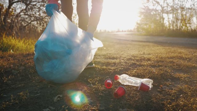 Volunteer woman picking up trash and plastics cleaning the park with a garbage bag. People and ecology. environment protection pollution problems, plastic waste caring about nature concept.