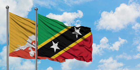 Bhutan and Saint Kitts And Nevis flag waving in the wind against white cloudy blue sky together. Diplomacy concept, international relations.