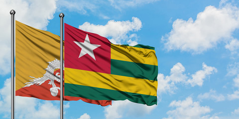 Bhutan and Togo flag waving in the wind against white cloudy blue sky together. Diplomacy concept, international relations.