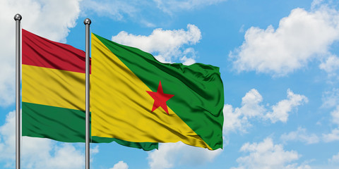 Bolivia and French Guiana flag waving in the wind against white cloudy blue sky together. Diplomacy concept, international relations.