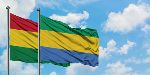 Bolivia and Gabon flag waving in the wind against white cloudy blue sky together. Diplomacy...