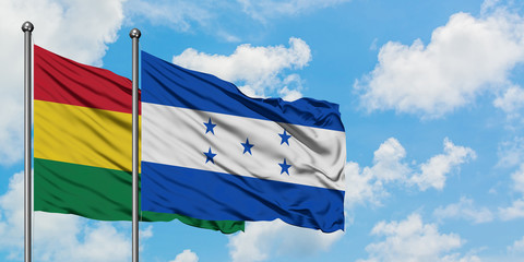 Bolivia and Honduras flag waving in the wind against white cloudy blue sky together. Diplomacy concept, international relations.