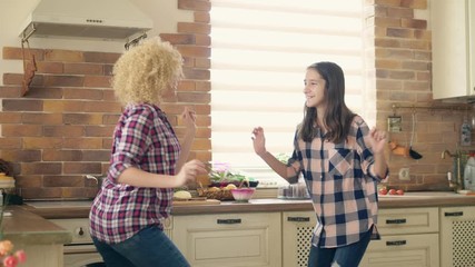 Dancing with mom. Cute teen daughter dancing in the kitchen with her loving mother