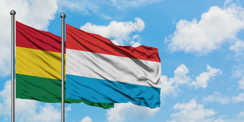 Bolivia and Luxembourg flag waving in the wind against white cloudy blue sky together. Diplomacy concept, international relations.