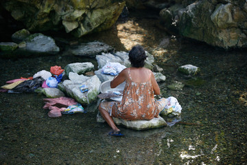 Filipino elderly woman washing clothes in the river. Philippines. Island Katiklan