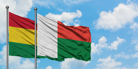 Bolivia and Madagascar flag waving in the wind against white cloudy blue sky together. Diplomacy concept, international relations.