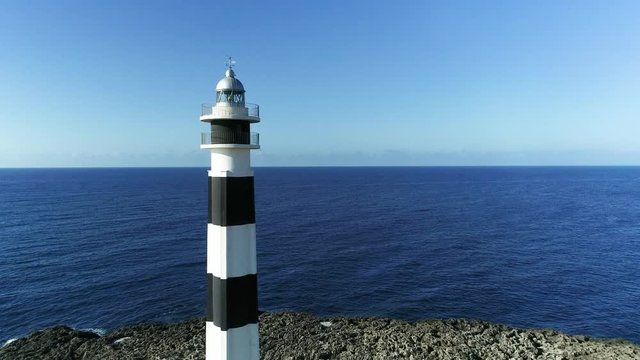 4K drone footage of  a black and white lighthouse in the morning on the island of Menorca, closeup shot