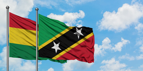 Bolivia and Saint Kitts And Nevis flag waving in the wind against white cloudy blue sky together. Diplomacy concept, international relations.